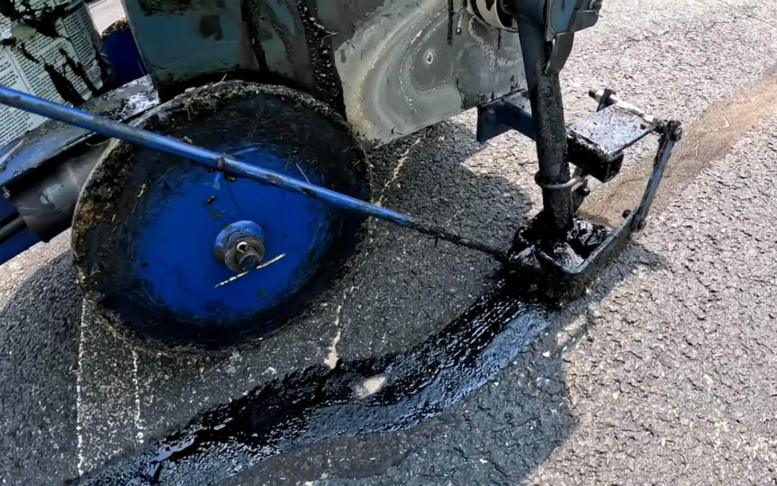 Worker sealing asphalt surface during pavement repair work